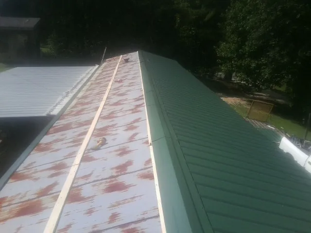 Old rusted panels beside newly installed green metal roofing — Wind Damage Roof Repair by Roofing Brothers in Annandale