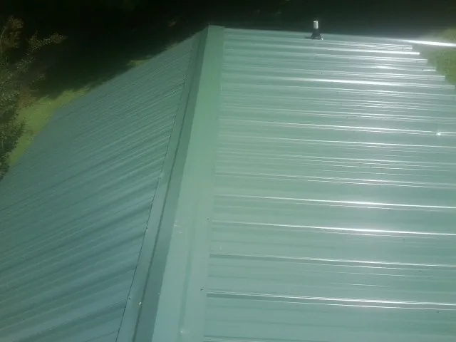 New green metal panels meeting at the ridge of a roof — Flat Roof Repair work by our crew in Annandale