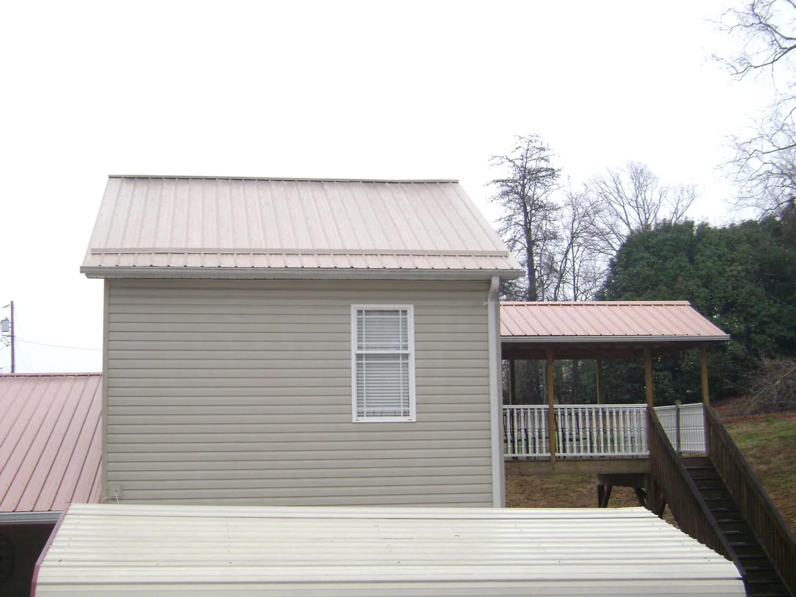 Tan metal roofs on a two story addition and attached porch, from a Roof Replacement job in Annandale